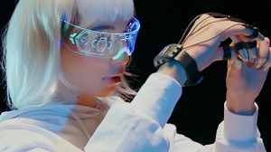 A young woman wearing a futuristic VR headset and a controller device in her hand slowly moves her hands - Free Stock Video