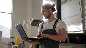 auto mechanic Portrait in backlight, car service, master Works in electronic computer Checks Technical condition, Diagnostics systems machine, repairman background Opens trunk