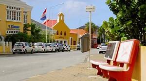 Willemstad , Curaçao - 01 05 2022: Bus stop on the vibrant and quaint urban streets of Punda, Willemstad, with Dutch flag in the background on the Caribbean island of Curacao.