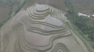 A farmer at work among massive rice paddy terrace fields in China - aerial view