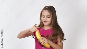 Girl dances with a banana. A girl peels a banana and eats a banana. Happy emotions of a hungry girl who was eating a banana.