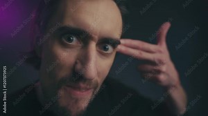 Humorous Young Man Close Up A young European man poses comically with bulging eyes and hands like a gun conveying a playful pantomime of shooting himself.