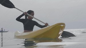 Beautiful woman kayaking in the ocean on a hot summer day.