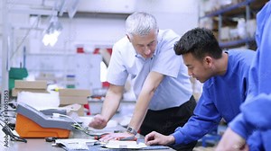 Happy male factory worker discussing work with his line manager