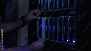 IT Engineer Inserts Hard Drive in Server Room and Enters Information Using a Flat Keyboard on Modern Screen Interface. Cluster Server Data Center. Close Up. Engineer hands.
