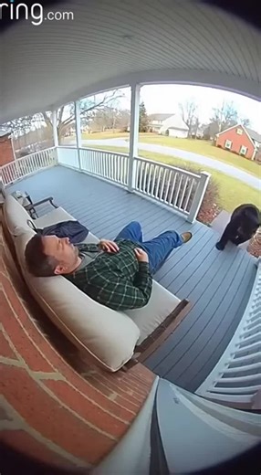 A man peacefully naps on his front porch, completely unaware that a massive black bear has wandered up and is sniffing him curiously. The moment he opens his eyes and realizes what's happening, the startled bear bolts away into the woods!
