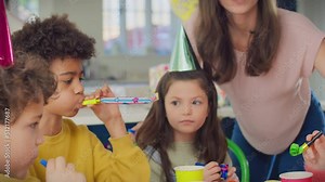 Children and parents at home celebrating birthday with party and blowers - shot in slow motion