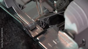 Overlock Sewing Machine. Close up stitches in slow motion. Machine serging the edges of fabric. Presser feet