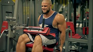 bald athletic man beard engages in leg exercises gym. He focuses on does leg extensions