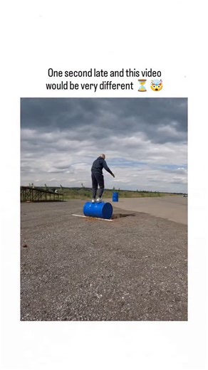 ViralSnap on Instagram: "- This 12-second video captures a heart-stopping stunt where timing is literally everything. A man stands atop a blue barrel in the middle of a runway, casually balancing as he prepares for a high-stakes trick. The tension builds as a luxury car speeds toward him at an incredible velocity. In a split-second display of perfect timing, the man jumps and pulls his legs into the barrel just as the vehicle roars directly over him. The car clears the barrel by a hair's breadth