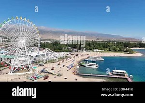 Cholpon-Ata, Kyrgyzstan October 4, 2025: Ferris wheel by Issyk-Kul Lake with scenic mountains in the background, a popular tourist spot.