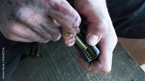 A soldier loads a machine gun clip with cartridges.