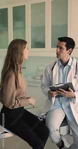 Pretty woman explaining disease symptoms to male doctor therapist. Physician holding clipboard writing health complaints in medical card, listen attentively female patient during her visit in hospital