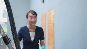 Asian Hotel maid come in front of room with tools and accessories for cleaning room and she knock the door before use keycard to go inside. Concept of hotel business support the system.