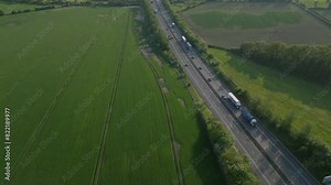 Flying over a motorway with busy traffic of lorries, cars and bikes driving, main transport hub connection in England the A42 with farm fields on either side of the road