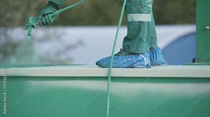 Worker is painting, using spray gun, applies coating composition to metal green construction