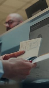 clip-3769721721-airport-check-in-counter-airline-agent-checking-documents