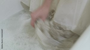 Washing dirty lace wedding dress in bathtub with soapy water and bubbles Stock Video
