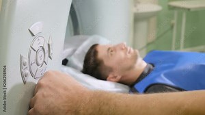 Closeup shot of male patient moving into a CT-scanner. Medical equipment: computer tomography machine in modern clinic. Health concept. Doctor presses settings button of CT MRI scanner. hd