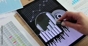 Employee examines diagrams on tablet screen with magnifier