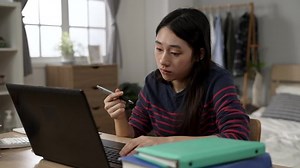 clip-1091521853-bored-asian-female-student-learning-home-playing