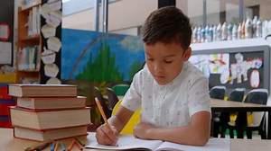 Premium stock video - Front view of asian schoolboy raising hand while studying on desk in classroom at school 4k