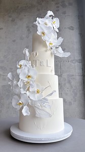 I was completely captivated by this elegant white-on-white wedding cake. textures, chocolate initials were breathtaking. The delicate rice paper ruffles and waffle paper leaves added an artistic flair. The final touch of fresh orchids made it a true dream wedding cake | K CAKE