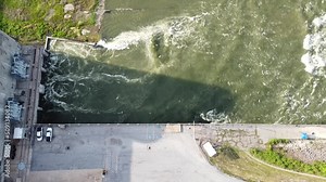 Strong water current generating from Denison dam hydroelectric power plant near parking lots pouring into spillway along Red River between Texas and Oklahoma, USA. Aerial releasing nature resource