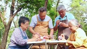 Group asian senior male and female friends join together to do recreational activities and showcase their talents holiday in the park. Show off your creativity paint colorful plaster vase soothingly.
