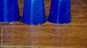 thimblerig.a hidden pea under one of the glasses moves them around the table