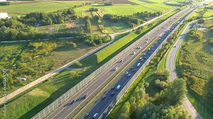 Aerial top view of highway road. Drone view of the elevated road, traffic junctions, and green garden. Transport trucks and cars driving on highway. Infrastructure in modern city.