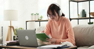A teenage girl participates in a video lesson, diligently taking notes in her notebook. With a focused expression and a pen in hand, she captures important information and key points from the lesson.
