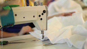 Sewing machine and white fabric, woman hand behind sewing, hand female, sewing manufacture, garment factory, woman working at a sewing machine
