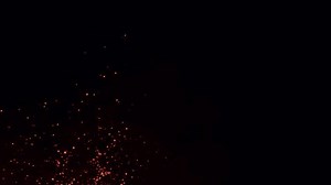 Hot burning fire sparks rising in the night sky. Ember fire particles flowing with the wind. Fire ashes closeup. Bonfire sparkles, firestorm, campfire, and natural disaster. Fiery glowing sparks. 4k.