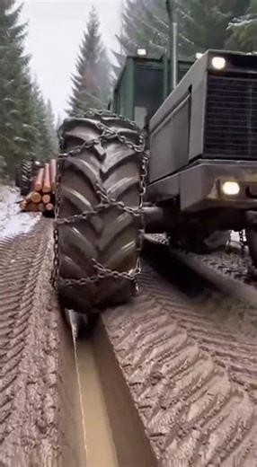 tractor struggling hauling logs on muddy roads