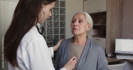 Doctor using stethoscope to listening heartbeat, breathing of senior patient, performing physical routine examination during medical visit at hospital. Heart or lungs check, health condition checkup