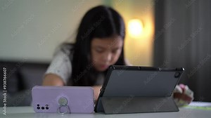 closeup tablet and smartphone with blur asian child or kid girl reading to write note on study online class or learn from home school by computer mobile phone or people studying learning by technology