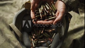 a soldier holds bullets for his machine gun and pours them into his helmet. slow motion. ammunition replenishment. loading weapons by an infantryman and preparing for battle. protection gear on war