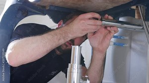 Plumber Fitting New Waste Trap To Wash Basin In Bathroom