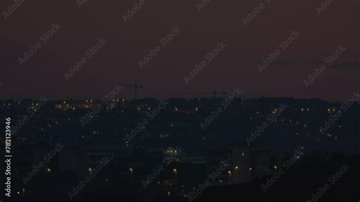 Top view of the city lights with construction tower cranes visible against the night sky