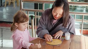 Korean Mother with Mixed Daughter Playing Korean Traditional Game Scratch Dalgona Sugar Caramel Candy with Toothpick in Shape of Triangle, Heart and Pine Tree at Gyeongamdong Railroad Town Old Market