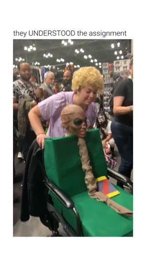 Rough Humor on Instagram: "This video shows two individuals performing a synchronized reenactment of a popular animated scene. ​The Subject The display features a two-person "living costume" based on characters from the television series SpongeBob. One person portrays Mary, the elderly daughter, while the other portrays her extremely aged mother, who is depicted as a withered, skeletal figure in a wheelchair. ​The Mechanism The illusion uses a modified wheelchair with a green fabric enclosure. T