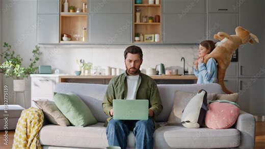 Dad freelancer typing laptop preteen daughter running around playing toy.