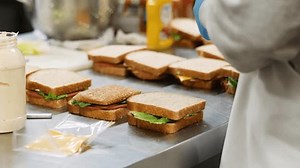 clip-3513987307-volunteer-making-sandwich-community-center-kitchen
