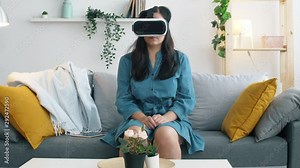 Young woman uses 3d virtual reality headset glasses. Girl seat on sofa in living room and play with vr. Slow motion 4k footage. Stock Video