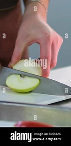 Hands slices a juicy fresh apples with a knife on a cutting board. Female hands cut red apple in pieces. Close up. Cutting apples for homemade apple