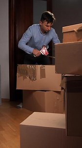vertical Man packing cardboard boxes for home relocation