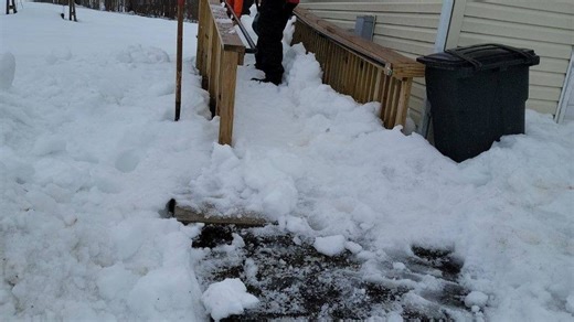 Volunteers help clear snow from wheelchair ramp for family