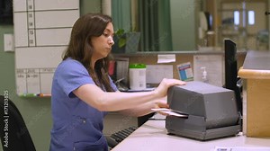 A nurse uses an addressograph to stamp hospital files at the nurse's station.