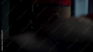 Rear view of a man preparing his boxing pear by wrapping it with sellotape in the dark room, sport concept. Fighter wrapping punching bag with brown sticky tape.